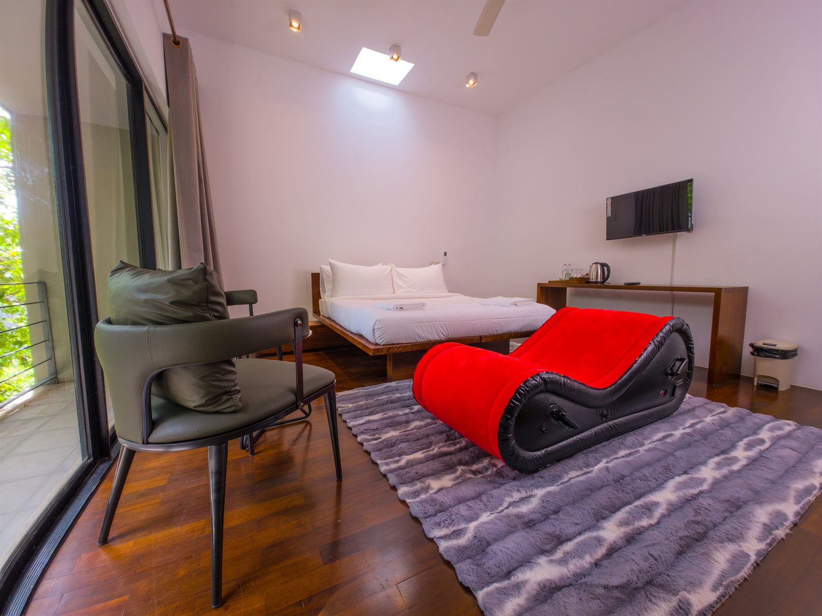Superior Room with bed, balcony, seating, and red lounge chair